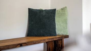 Two pillows on a wooden bench against a plain wall.