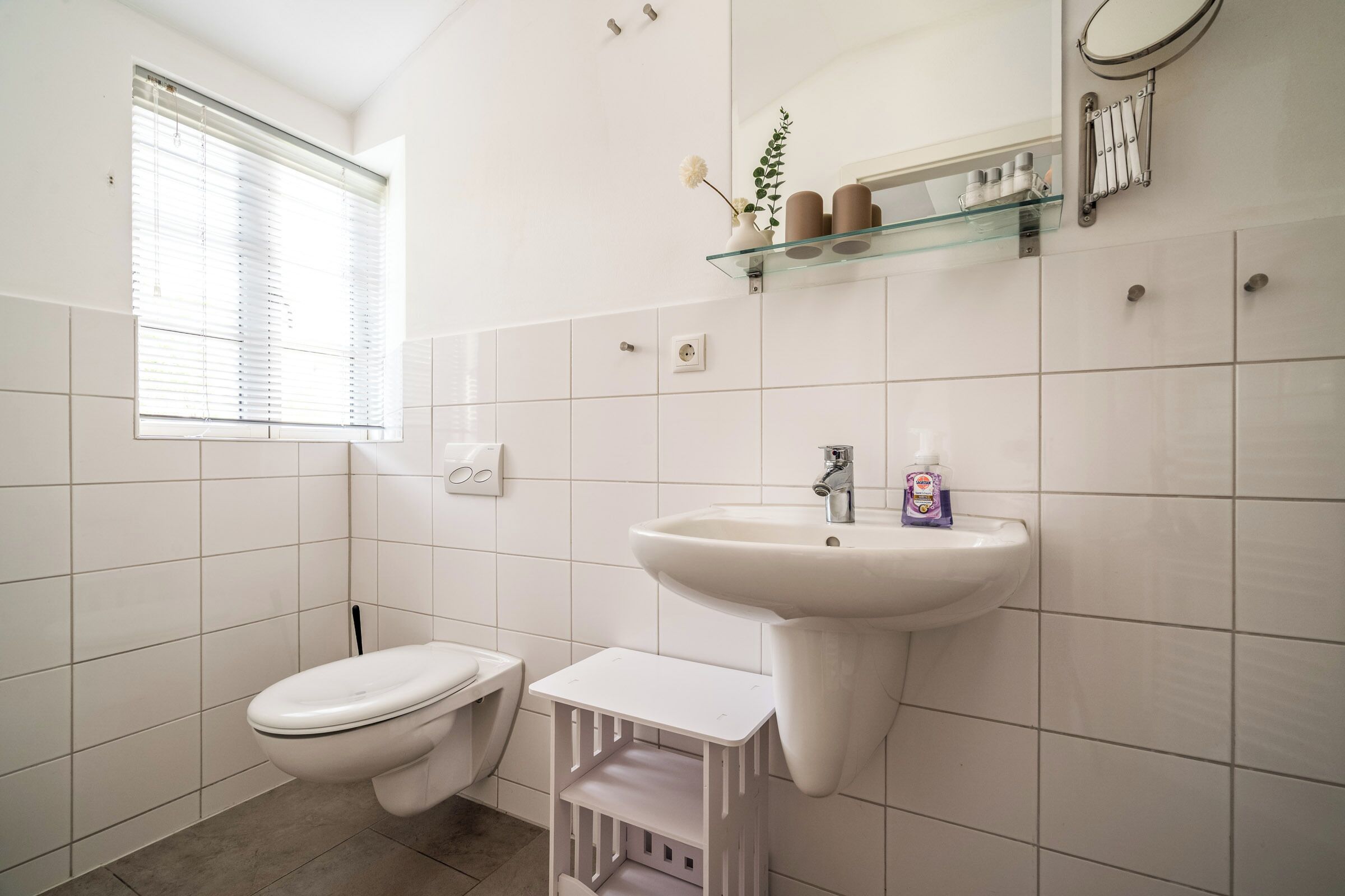 A bathroom with a toilet, sink, and window.