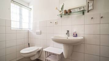 A bathroom with a toilet, sink, and window.