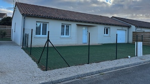 Un bâtiment d’un seul étage, doté d’un toit en tuiles, d’une cour clôturée et d’une allée gravillonnée.