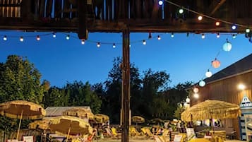 An outdoor seating area with thatched umbrellas and string lights.
