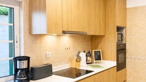 Une cuisine moderne avec des meubles en bois, une machine à café noire, un four à micro-ondes et un grille-pain.