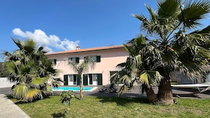 Un bâtiment à deux étages doté d’une piscine, entouré de palmiers et d’une pelouse.