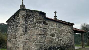 Un pequeño edificio de piedra con dos cruces en la parte superior, techo de tejas y suelo adoquinado.