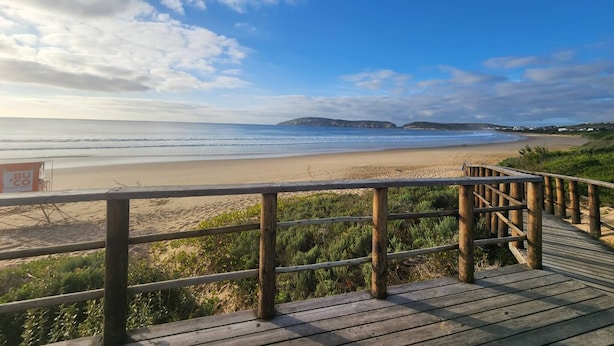 Una playa con un paseo marítimo de madera y una torre de salvavidas.