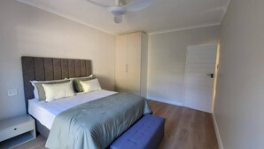 Un dormitorio con cama, banco, armario y puerta.
