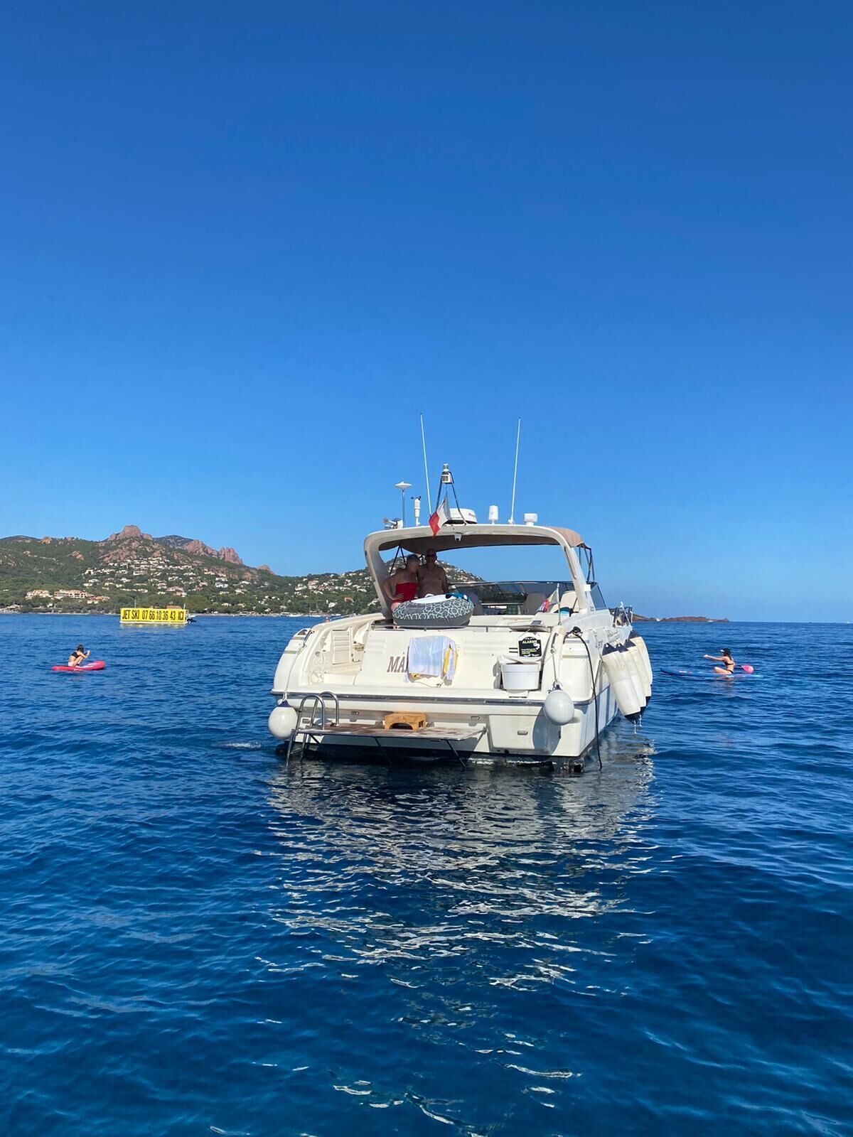 A boat with a cabin, a lifebuoy, and a flag on top.