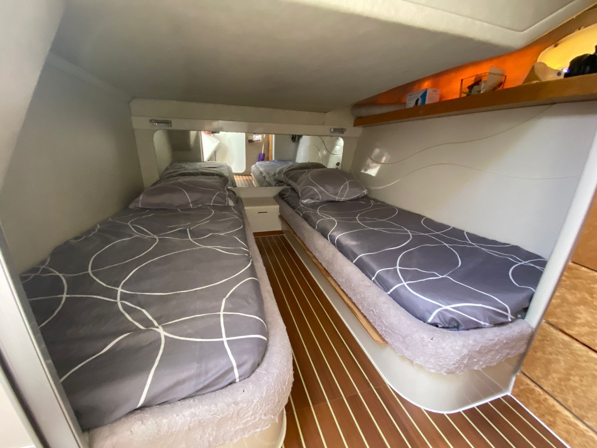 Ein kompaktes Wohnmobil-Interieur mit zwei Schlafbereichen, einer Küchenzeile und einem kleinen Ablagefach.