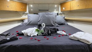 Ein ordentlich gemachtes Bett mit Kissen, eine schwanenförmige Handtuchgestaltung und Rosenblüten.
