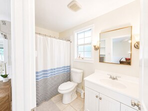 Ein Badezimmer mit Toilette, Waschbecken, Spiegel und Duschvorhang.