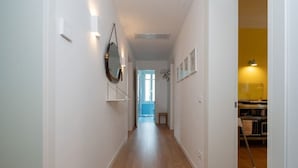 A hallway with wooden flooring, white walls, and a door leading to a room with a yellow wall and a kitchen area. - Charming Venetian  Retreat-3 Bedrooms, Dorsoduro (Venezia)