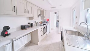 Una cucina moderna con mobili bianchi, forno integrato, microonde e lavello in acciaio inossidabile.