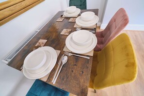 A dining table set with white plates, bowls, cutlery, and coasters. - Modern Apartments in Central Derry I Each Apartment Sleeps 4 (Derry/Londonderry)