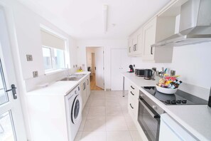 A modern kitchen with a washing machine, oven, and a bowl of snacks on the counter. - Modern Apartments in Central Derry I Each Apartment Sleeps 4 (Derry/Londonderry)