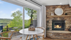 Una habitación con chimenea de piedra, un espejo redondo y vistas a un lago.