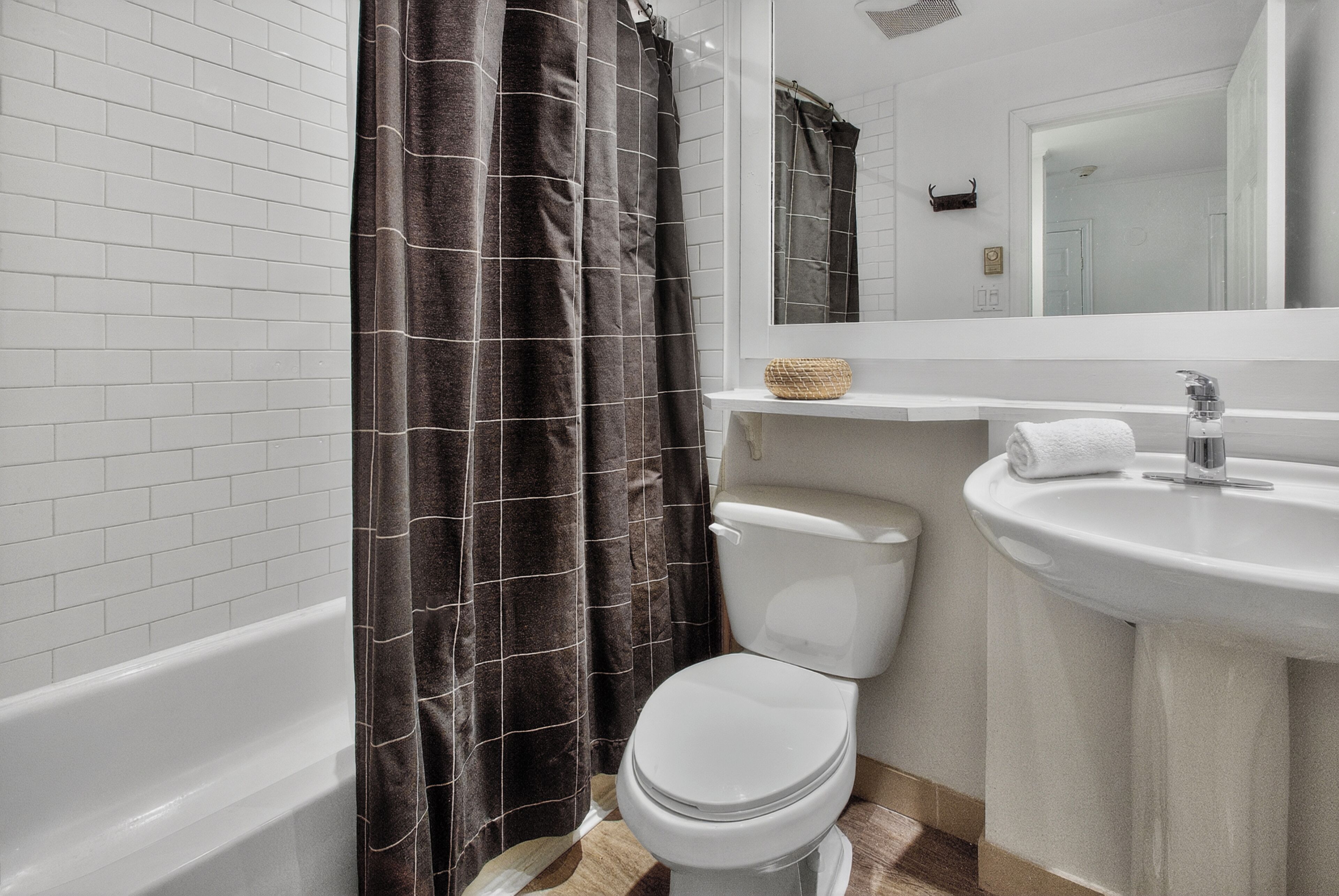 Une salle de bain avec des toilettes blanches, une baignoire, un lavabo et un rideau de douche.