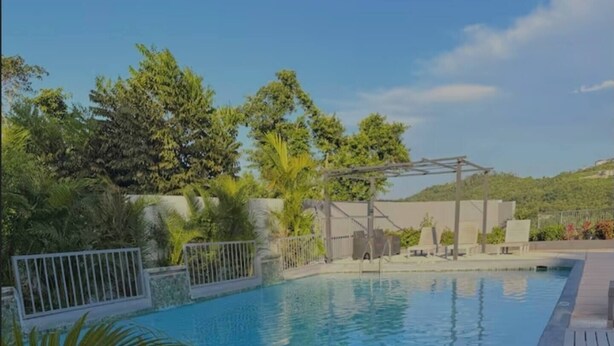 Ein Schwimmbecken mit klarem, blauem Wasser, umgeben von Pflanzen und einer Pergola.
