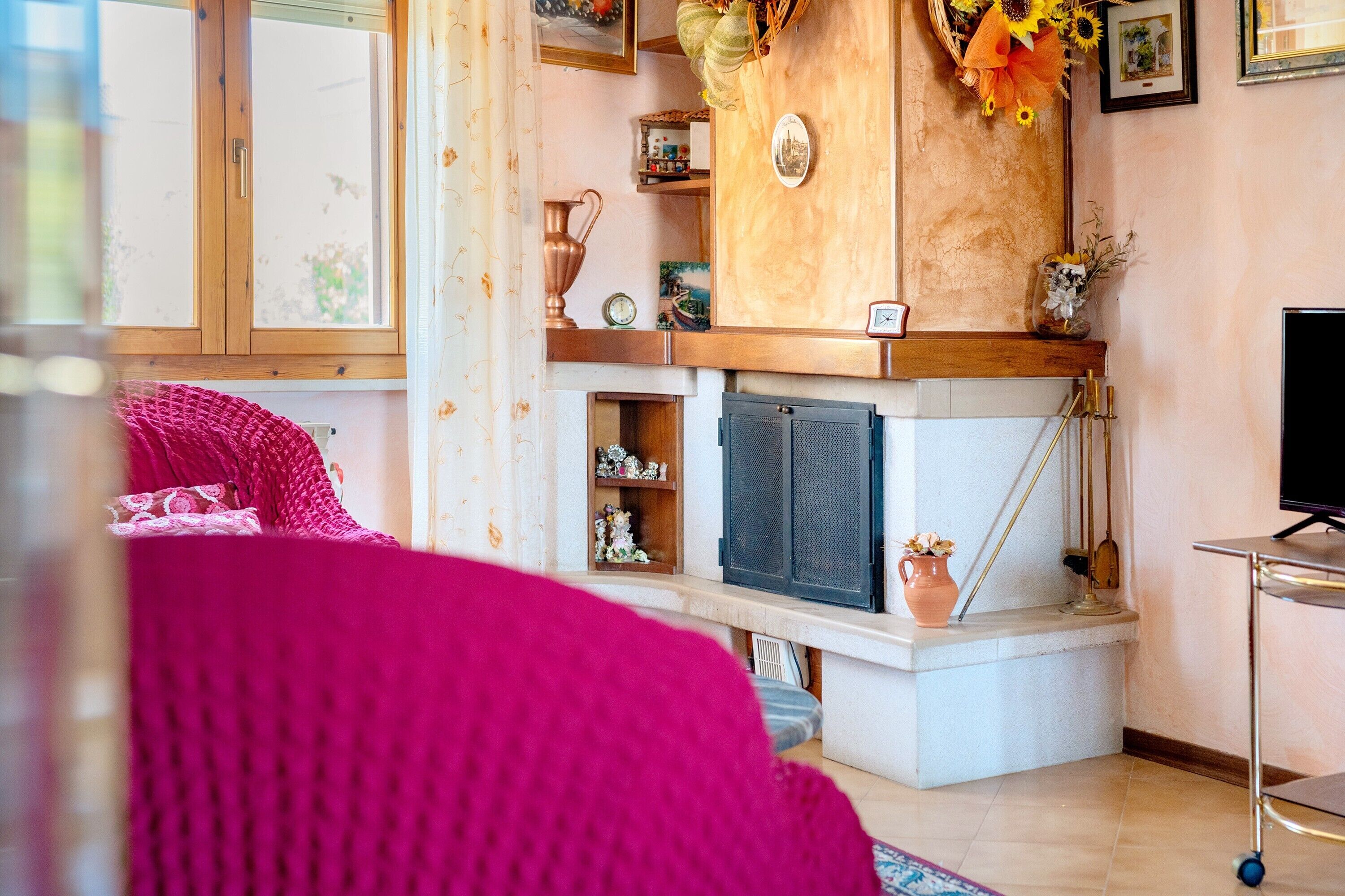 Una sala de estar con chimenea, televisor y varios objetos decorativos en estantes.