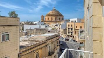 A view from a balcony overlooking a city street with a historic building in the background.