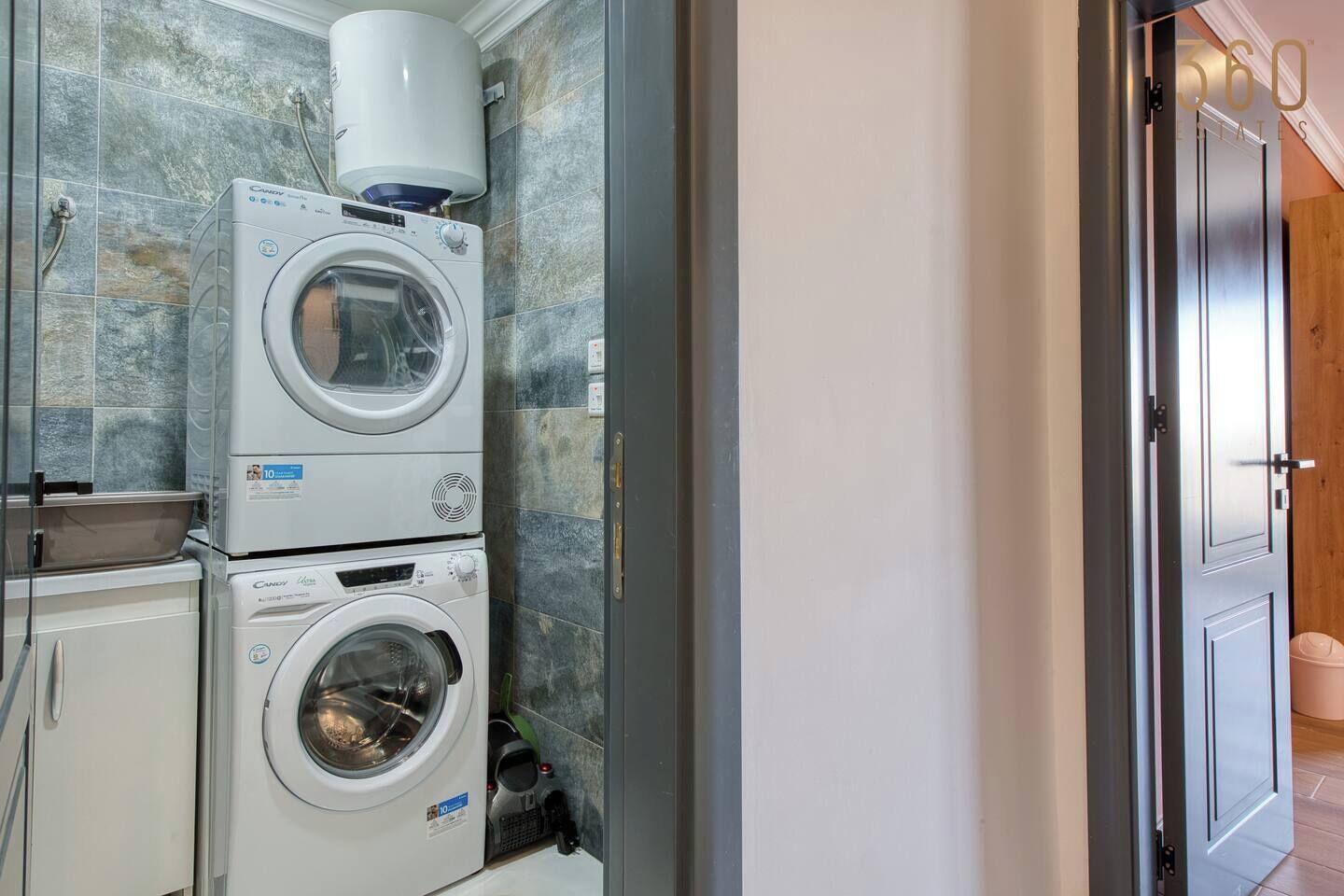A laundry area with stacked washing machines and a water heater.