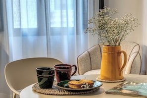 Ein Tisch mit einer Tasse, einem Teller mit einem Muffin, einer Vase mit Blumen und einer Zeitschrift.