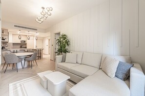 A modern living room with a sofa, coffee table, and dining area. - Stylish Renovated 1BR At Prime JBR Location (Dubai)