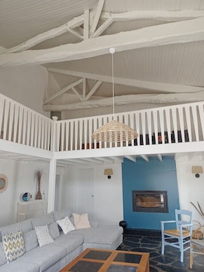 Un vaste espace de vie doté d’un plafond haut, de rampes blanches, d’un canapé gris, d’une table basse et d’un mur d’accent bleu.