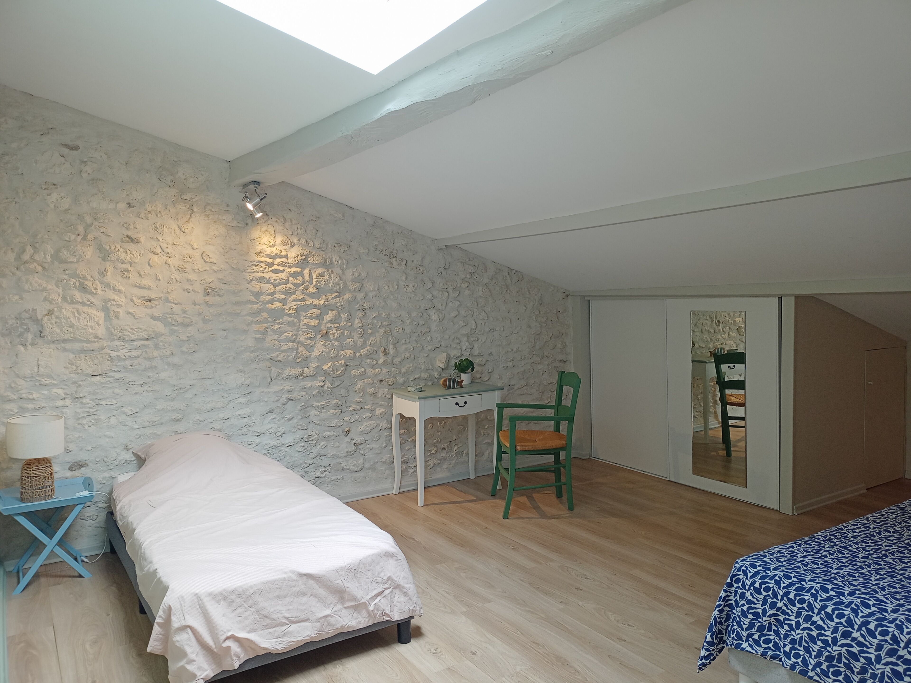 Une chambre avec un plafond en pente, un lit, un bureau, une chaise et une armoire.