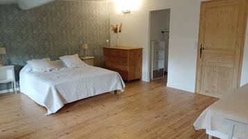 Une chambre à coucher comprenant un lit, une commode en bois, une table de chevet et une armoire.
