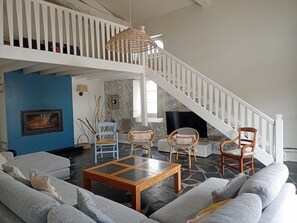 Un salon avec un escalier, une télévision et une cheminée.