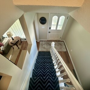 Un escalier recouvert d’une moquette à motifs menant à une porte dotée d’une fenêtre.