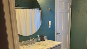 Une salle de bain avec un lavabo en marbre, un grand miroir et un porte-serviettes.