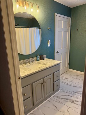 Une salle de bain avec un lavabo en marbre, un grand miroir et un porte-serviettes.