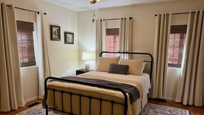 Une chambre à coucher avec un lit, une table de chevet, une lampe et des rideaux.