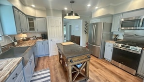 A modern kitchen with a central island, stainless steel appliances, and light blue cabinetry.