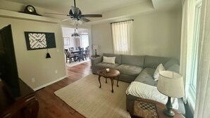 Un salon comprenant un canapé, une table basse, une lampe et un ventilateur de plafond.