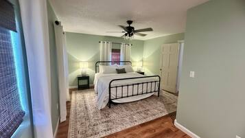 A bedroom with a bed, bedside lamps, a ceiling fan, and a patterned rug.