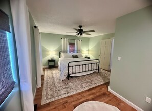 Une chambre à coucher avec un lit, des lampes de chevet, un ventilateur de plafond et un tapis à motifs.
