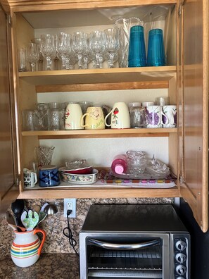 Eine Küche mit einem Toaster, einem Holzkabinett mit Gläsern und einer bunten Tasse.
