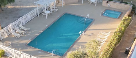 Une piscine extérieure dotée d’une terrasse, de chaises longues et d’un petit pavillon.