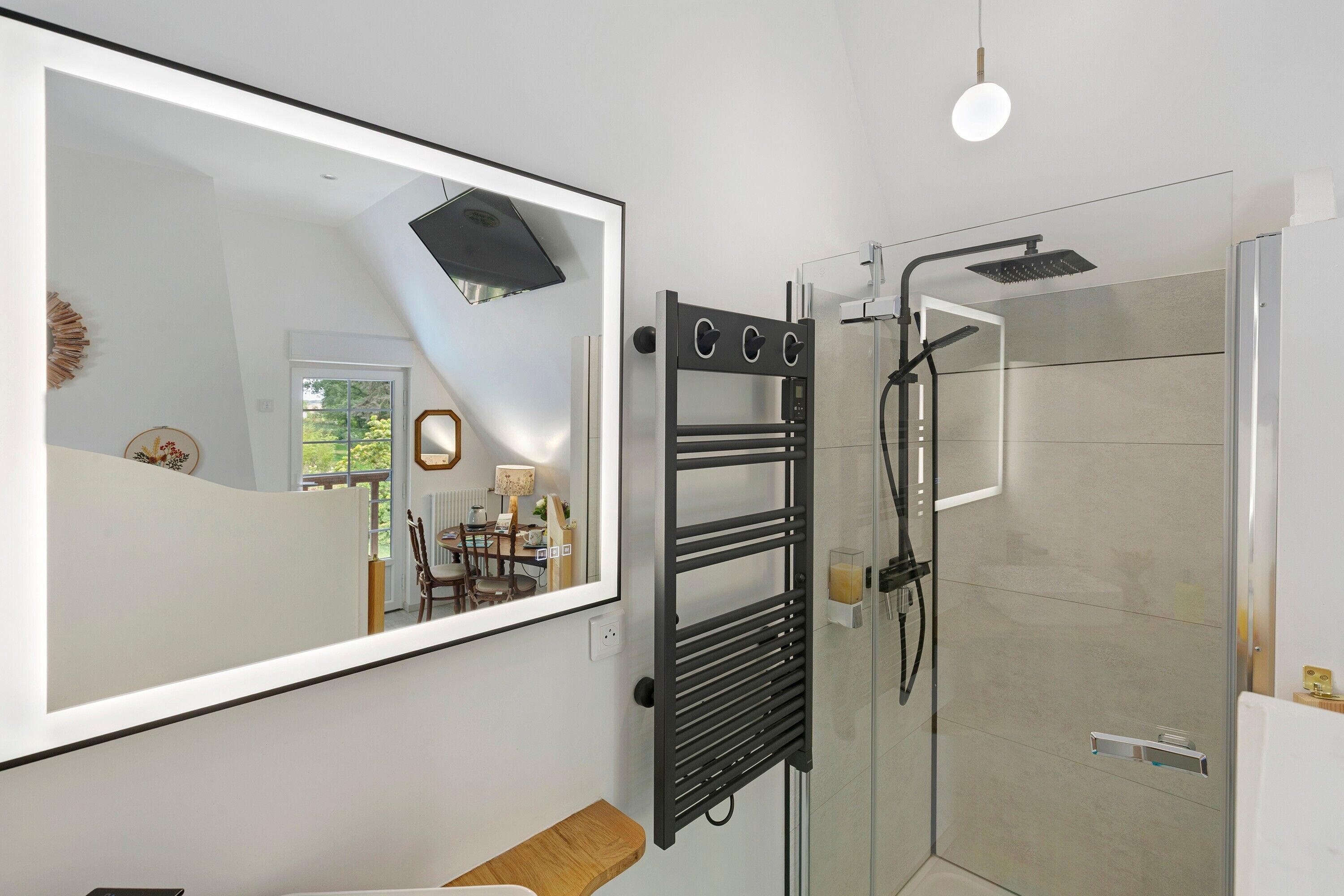 Une salle de bain moderne avec une douche à parois de verre, un porte-serviettes et un grand miroir.