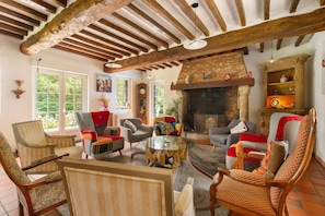 A cozy living room with a fireplace, wooden beams, and comfortable seating. - Fleur de Lin Guest Room (Pleine-Sève)
