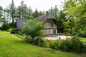Une maison traditionnelle à colombages dotée d’un patio et d’un espace extérieur aménagé pour s’asseoir.
