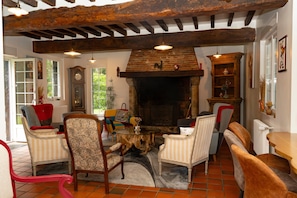 A cozy living room with a fireplace, wooden beams, and comfortable seating.