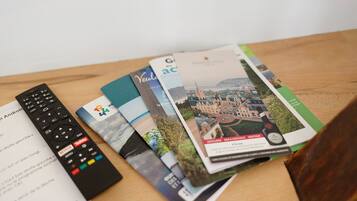 Une télécommande, un manuel d’utilisation et un magazine, posés sur une surface en bois.