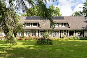 A traditional half-timbered building with solar panels on the roof, surrounded by a well-maintained garden.