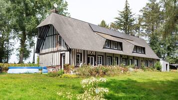 A large, two-story house with a steeply pitched roof, surrounded by a well-maintained lawn and trees.