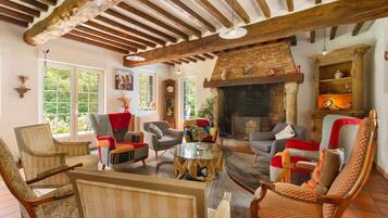 A cozy living room with a fireplace, wooden beams, and comfortable seating.