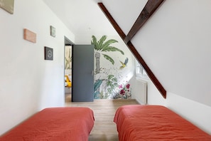 Een hal met twee bedden, een deur naar een kamer en een groot muurschildering met tropische planten en een papegaai.