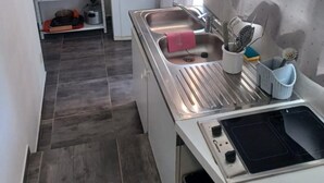 A compact kitchen with a microwave, sink, and a small dining area. - Apartment with pool and garden (Boisset-et-Gaujac)